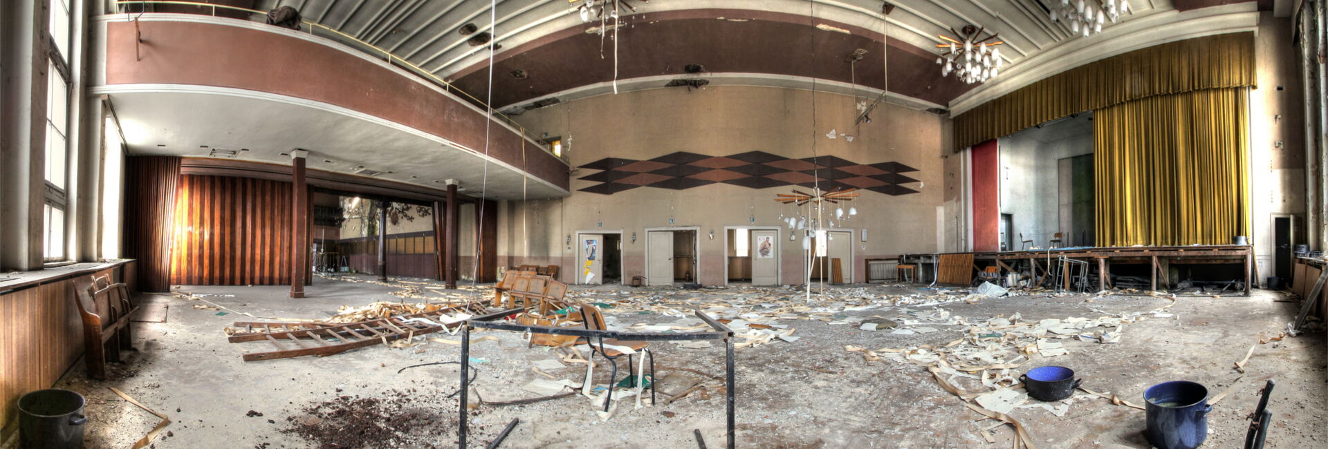 Verlassener Saal mit Bühne und Balkon.